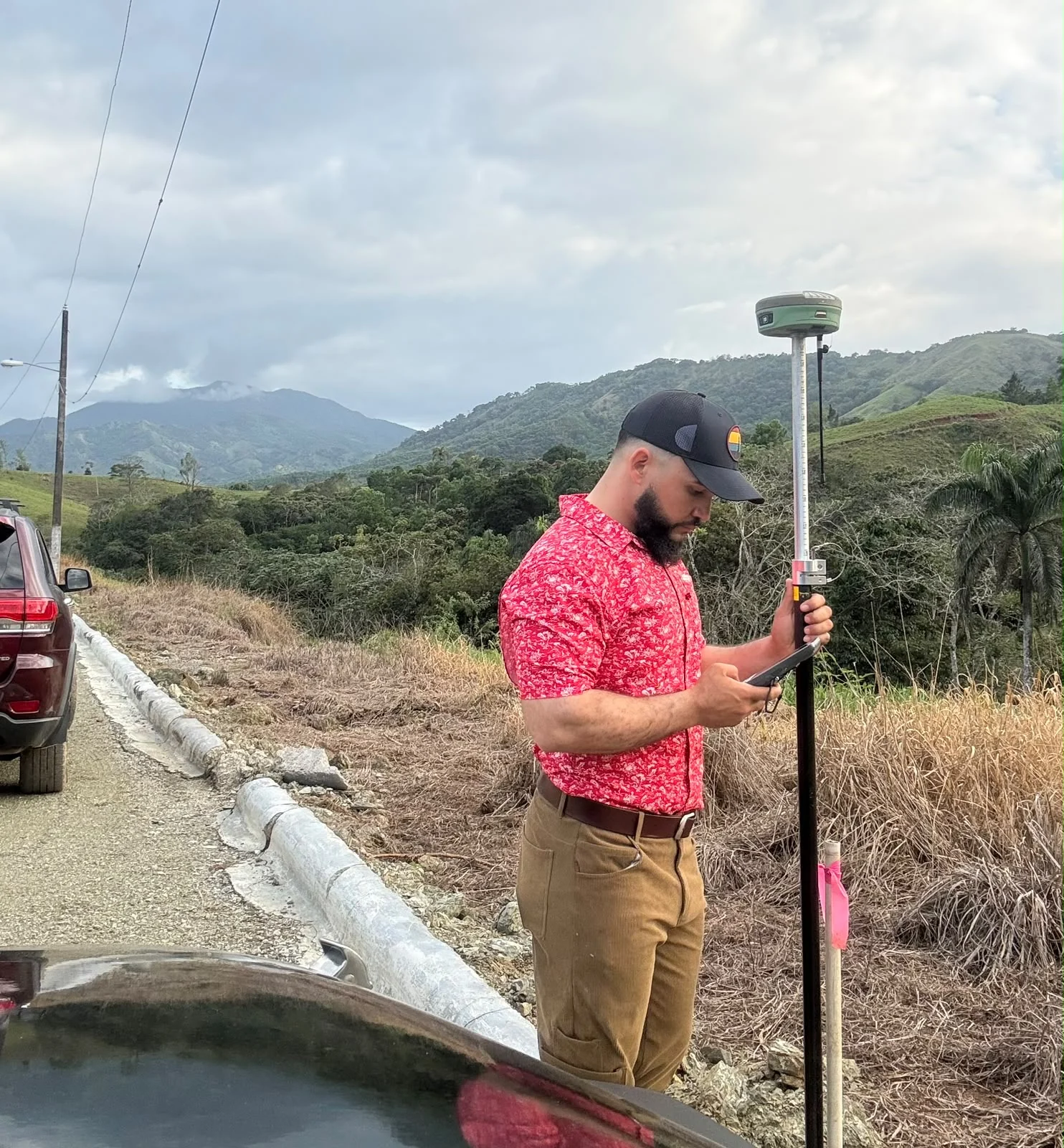 Anderson Gutiérrez trabajando con equipo GNSS frente a un paisaje montañoso
